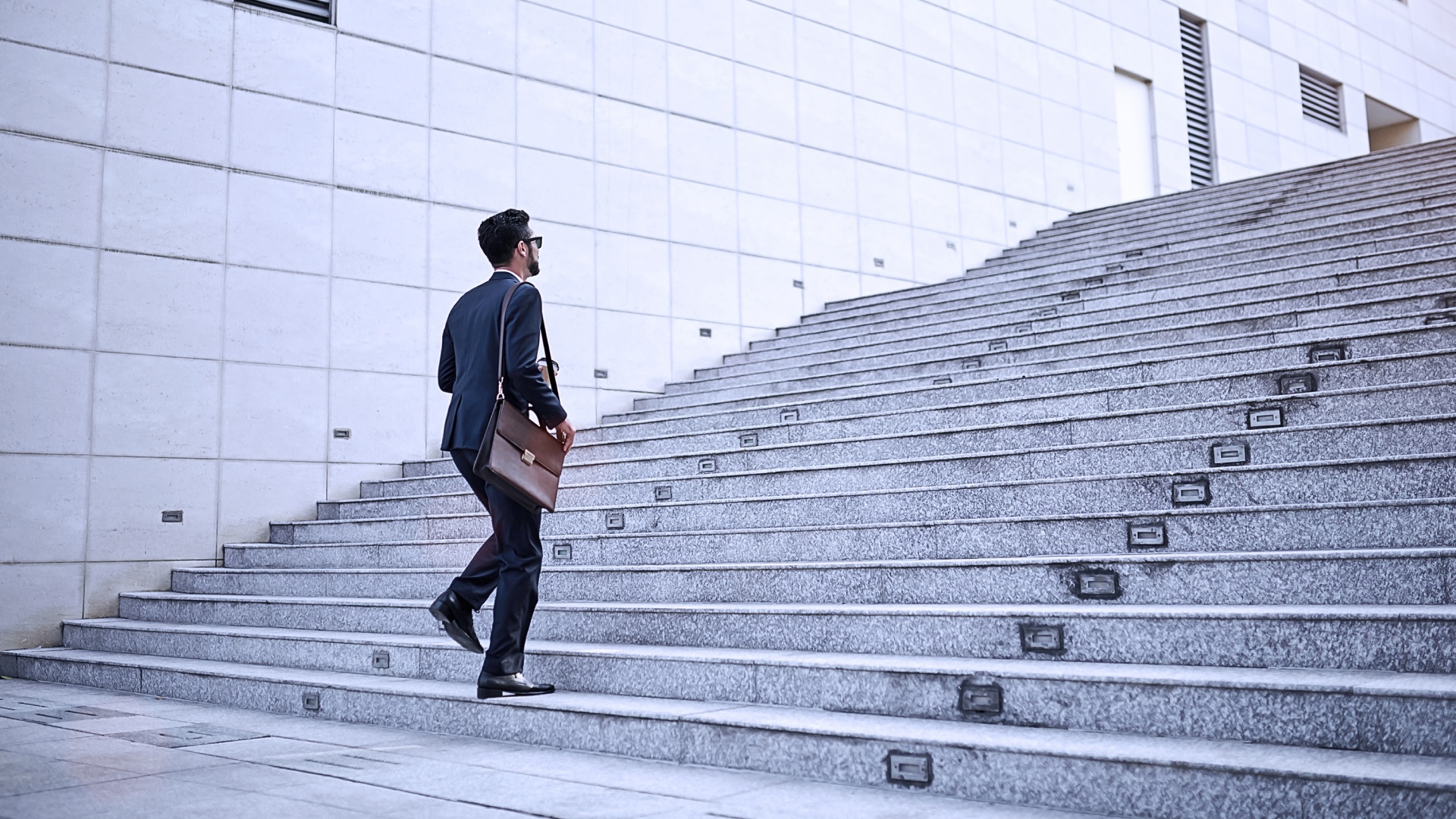 Mann der im business outfit eine Treppe nach oben laeuft